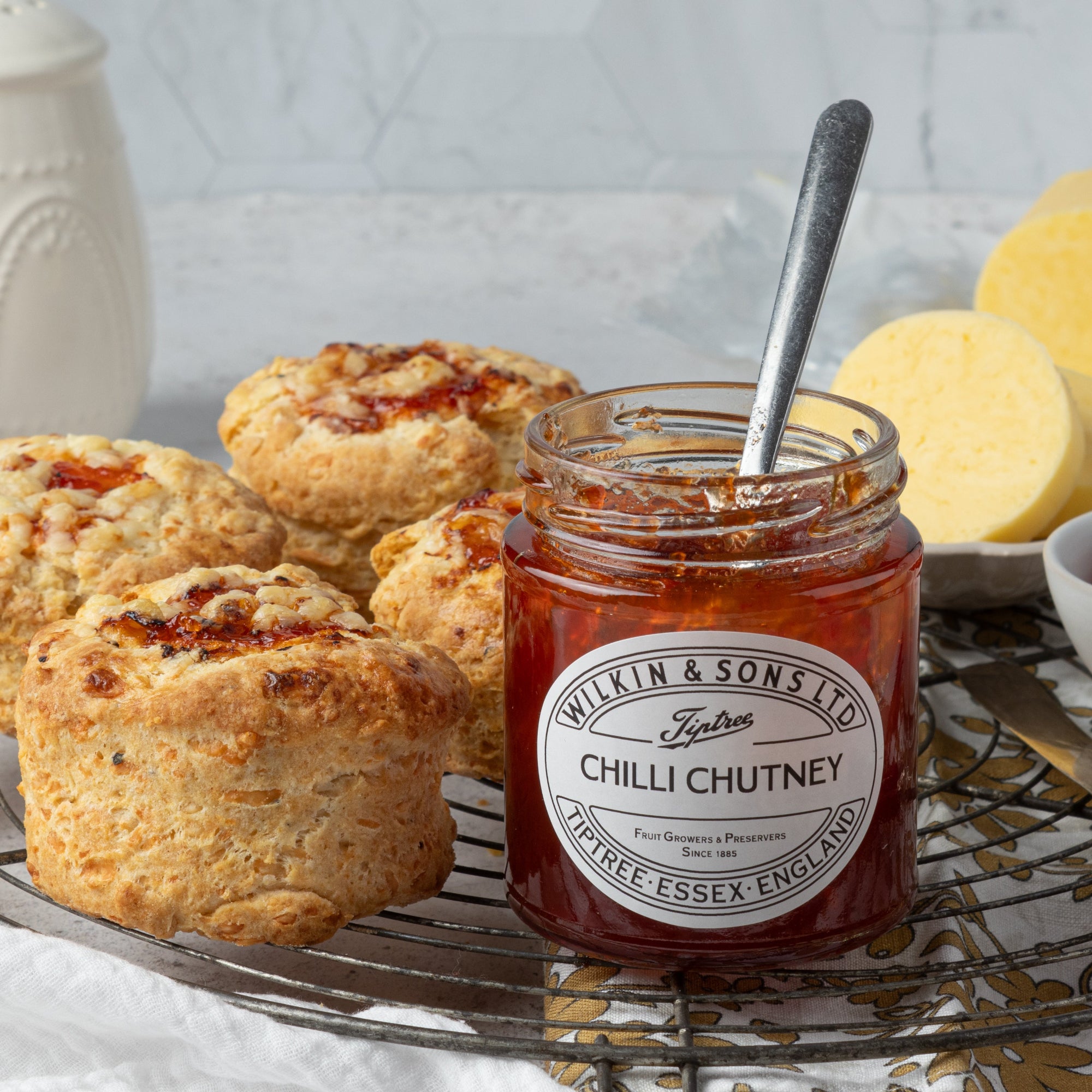 Jar of Wilkin & Sons Chilli Chutney with scones on a table