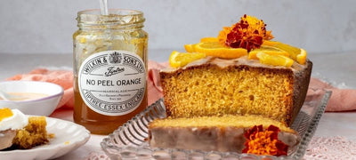 An orange loaf cake next to a jar of Tiptree No Peel Orange Marmalade