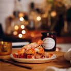 Plate of food on a table with a blurred background featuring lights and kitchen items.