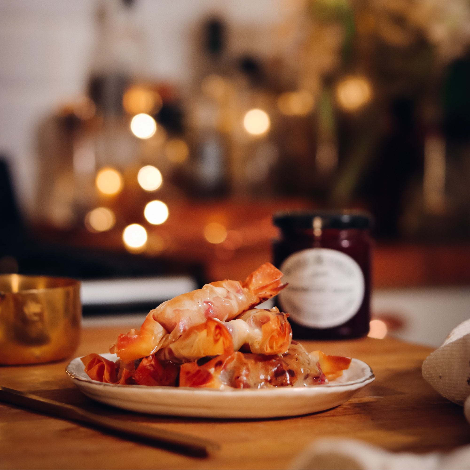 Plate of food on a table with a blurred background featuring lights and kitchen items.