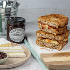 Stack of grilled sandwiches with cheese and chutney on a table with a jar of chutney.