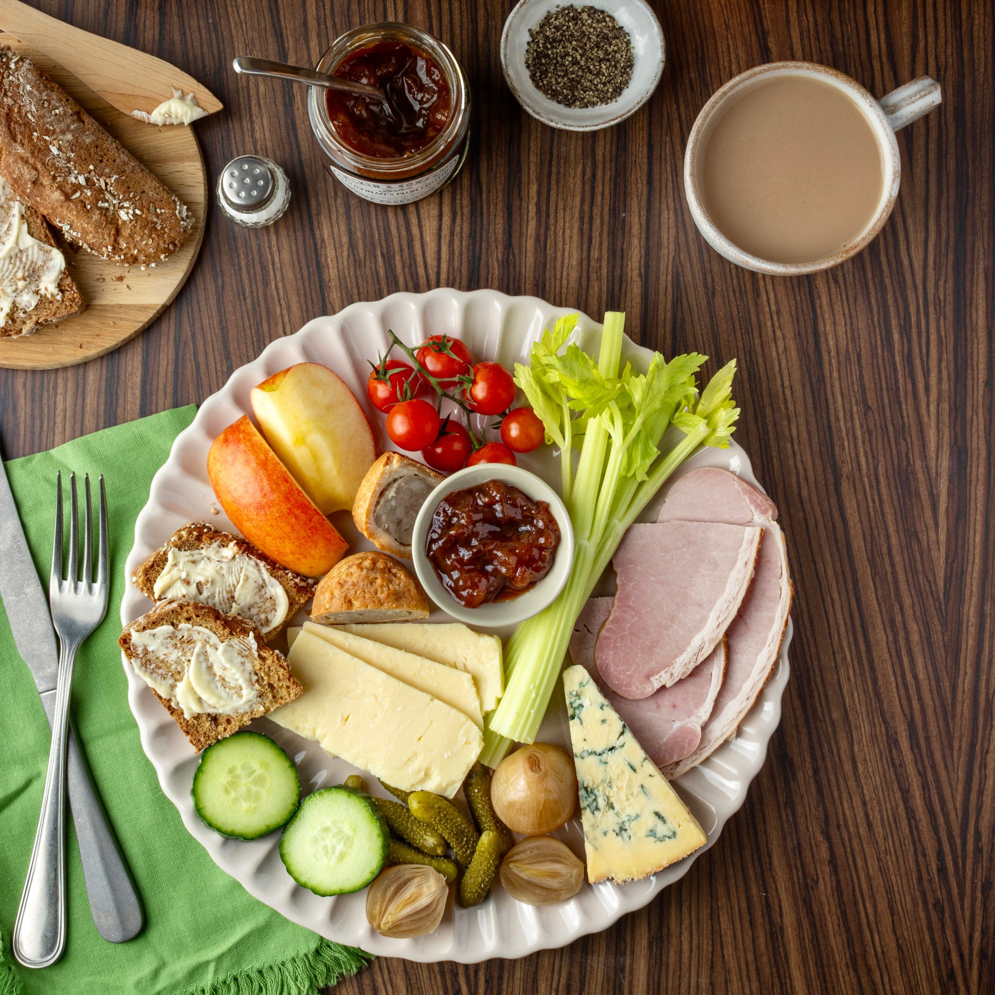 Platter of assorted meats, cheeses, and vegetables with a cup of coffee on a wooden table.
