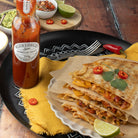 Quesadillas on a plate with a bottle of barbecue sauce and ingredients in the background.