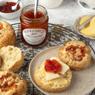 Scones with cheese, chutney and butter on a plate, accompanied by a jar of chutney.