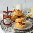 Stack of scones with chutney on a plate, accompanied by a jar of chutney.