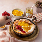Dutch baby pancake with fruit and marmalade on a pink tablecloth