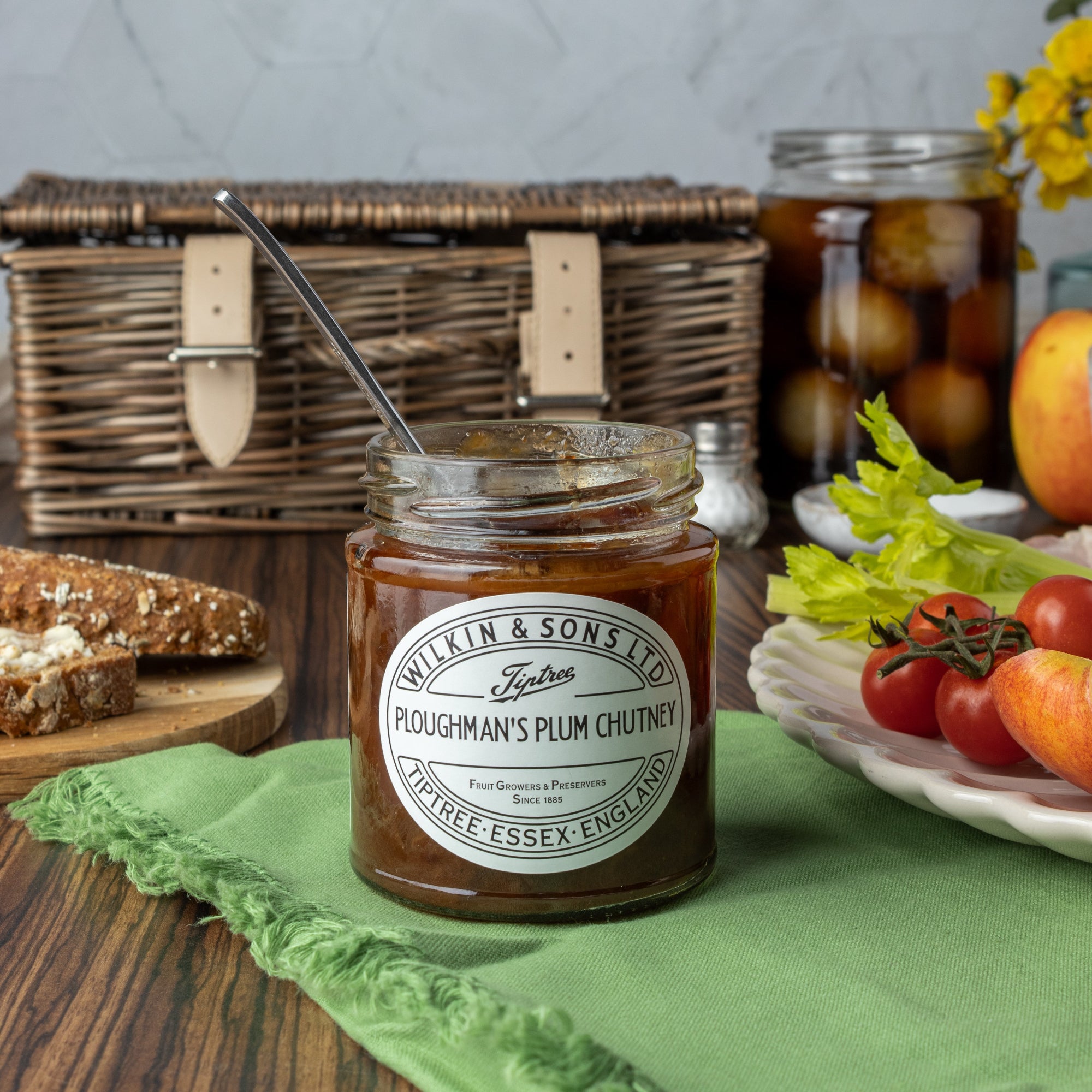 Jar of ploughman's plum chutney with a picnic setup in the background